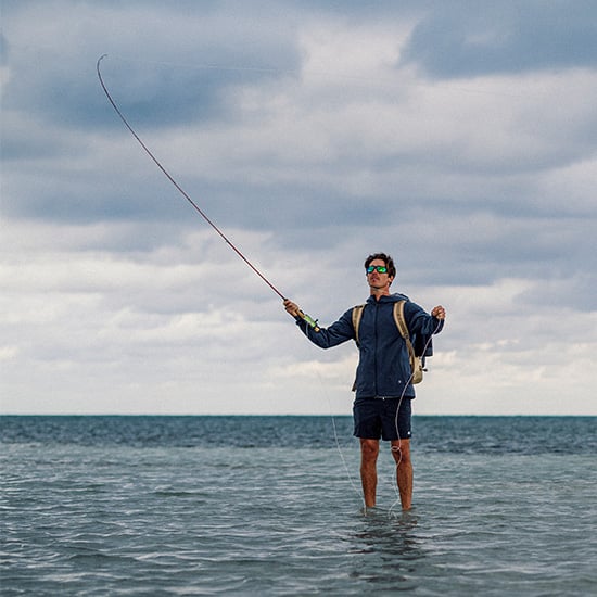 Man fishing on a surfboard smiling wearing sunglasses Man fishing on a surfboard smiling wearing sunglasses